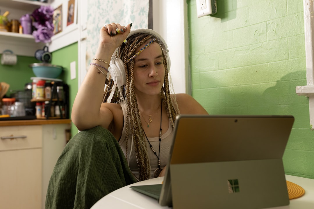 A woman with dreadlocks working on a laptop in a kitchen at Roanoke College.