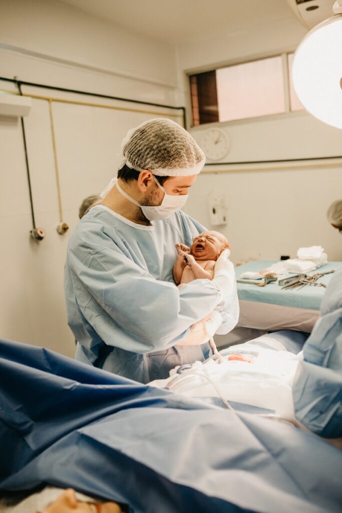 a nurse in lab suit and mask carrying newborn baby